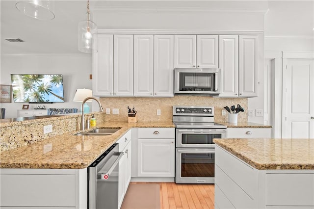 kitchen with appliances with stainless steel finishes, decorative light fixtures, white cabinetry, sink, and ornamental molding