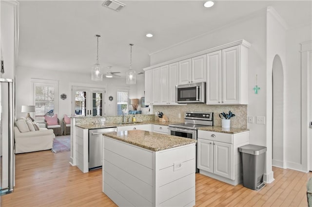 kitchen with a kitchen island, white cabinetry, hanging light fixtures, kitchen peninsula, and stainless steel appliances