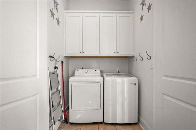 washroom featuring light tile patterned floors, washing machine and dryer, and cabinets