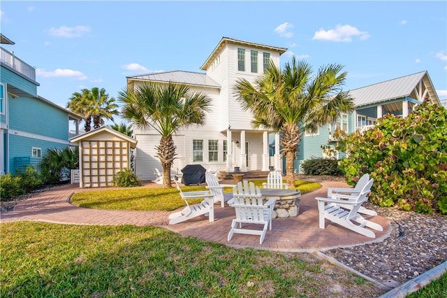 rear view of property featuring an outdoor fire pit, a lawn, a shed, and a patio area