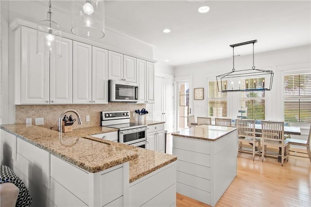 kitchen with pendant lighting, white cabinetry, backsplash, stainless steel appliances, and light stone countertops