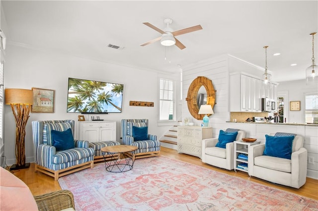 living room featuring hardwood / wood-style floors, crown molding, and ceiling fan