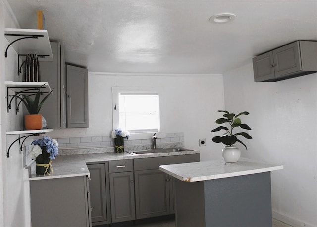 1110 Elgin St, Corpus Christi, TX 78405 - kitchen featuring gray cabinetry, open shelves, a sink, light countertops, and a center island
