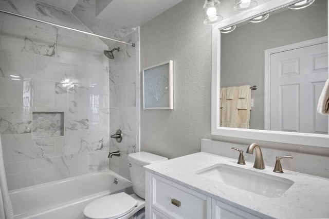 full bath with toilet, vanity, shower / bath combination, and a textured wall