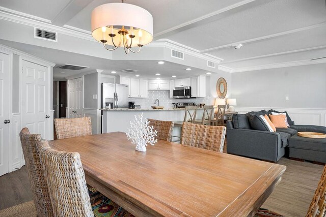 dining room with a chandelier, visible vents, crown molding, and wood finished floors