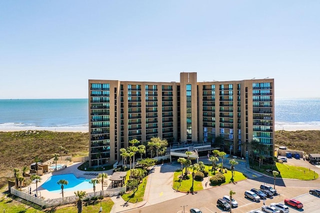 view of property featuring a community pool, a view of the beach, and a water view