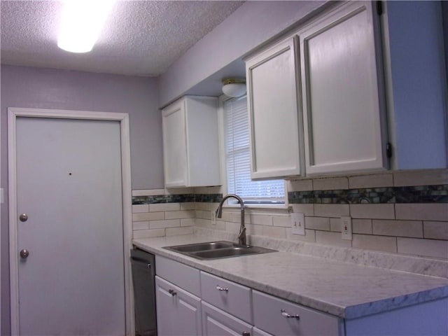 kitchen with backsplash, white cabinetry, sink, and a textured ceiling