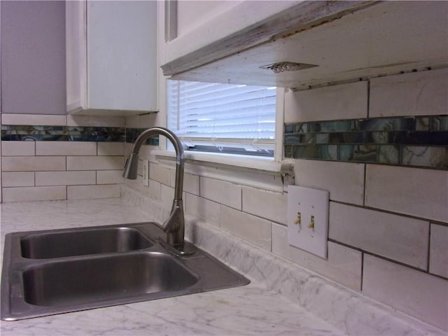 interior details with a sink, backsplash, and light countertops