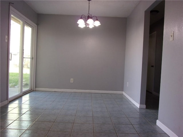 spare room featuring tile patterned floors, baseboards, and a chandelier