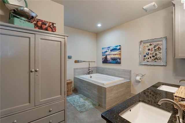 bathroom with a relaxing tiled tub, vanity, and concrete flooring