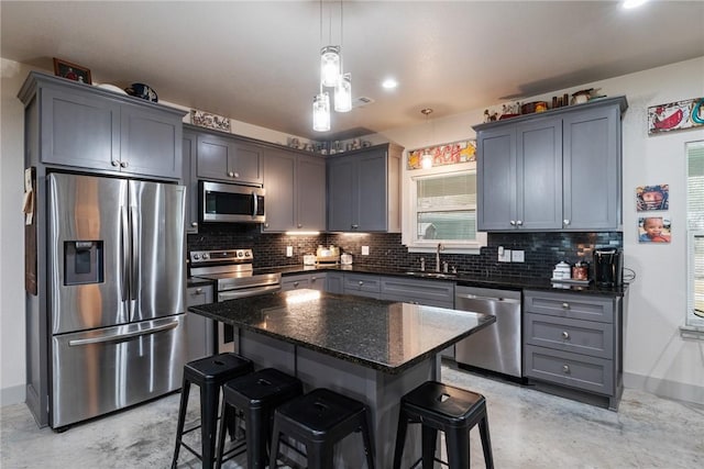 kitchen with a kitchen island, appliances with stainless steel finishes, a breakfast bar, and decorative light fixtures