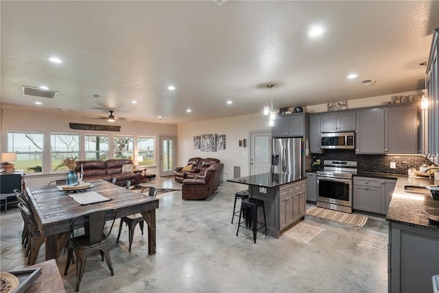 kitchen featuring sink, appliances with stainless steel finishes, gray cabinetry, hanging light fixtures, and a kitchen breakfast bar