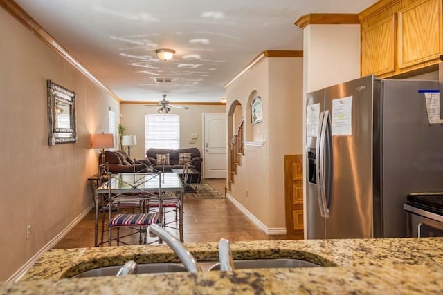 kitchen featuring sink, light stone counters, ornamental molding, ceiling fan, and stainless steel fridge with ice dispenser