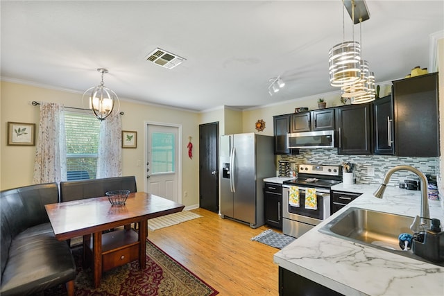 kitchen featuring sink, light hardwood / wood-style flooring, ornamental molding, decorative light fixtures, and stainless steel appliances