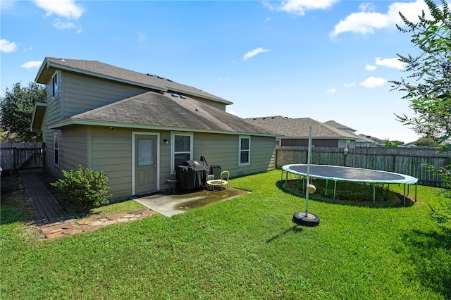 rear view of property with a lawn and a trampoline