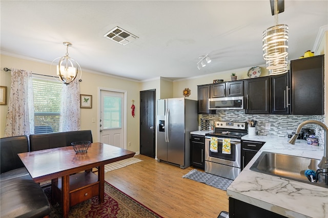 kitchen featuring hanging light fixtures, stainless steel appliances, light wood-type flooring, and sink