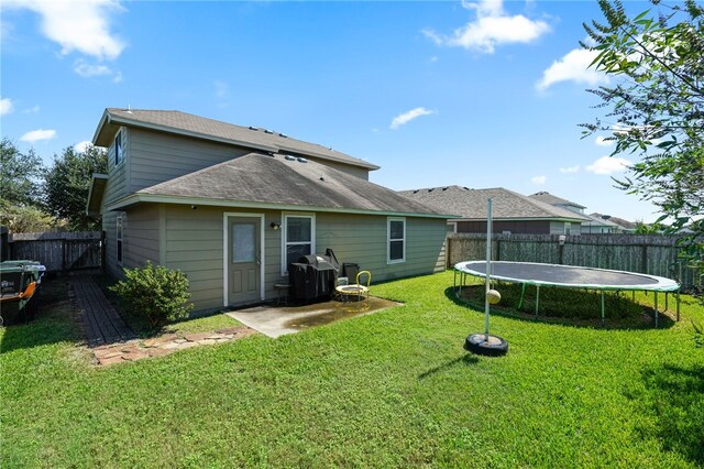 rear view of property with a trampoline and a lawn