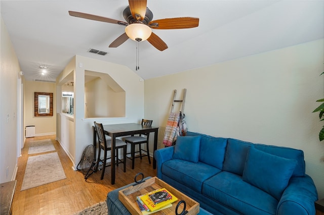 living room with ceiling fan, light hardwood / wood-style floors, and lofted ceiling