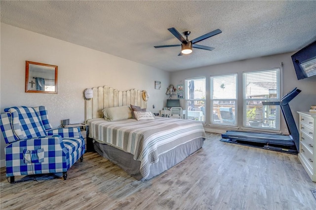 bedroom with ceiling fan, light hardwood / wood-style floors, and a textured ceiling