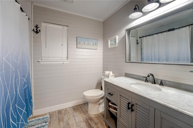 bathroom featuring vanity, hardwood / wood-style floors, wooden walls, and toilet