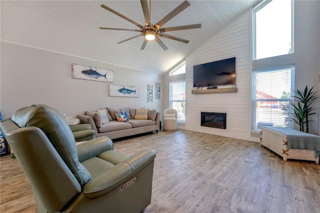 living room with ceiling fan, high vaulted ceiling, a fireplace, and light hardwood / wood-style flooring