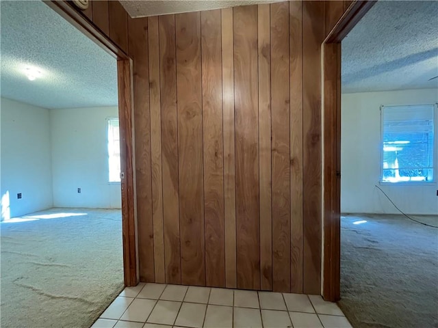 hall featuring light carpet and a textured ceiling