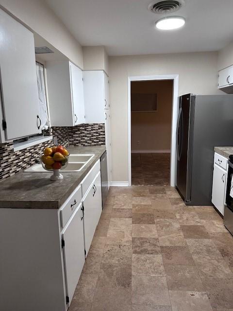 4633 Wilma Dr, Corpus Christi, TX 78412 - kitchen with white cabinets, decorative backsplash, appliances with stainless steel finishes, and stone finish floors