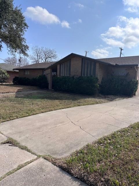 4633 Wilma Dr, Corpus Christi, TX 78412 - view of side of property featuring brick siding, concrete driveway, and a lawn