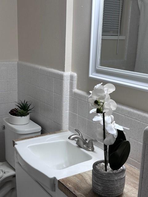 4633 Wilma Dr, Corpus Christi, TX 78412 - bathroom featuring tile walls, toilet, and vanity