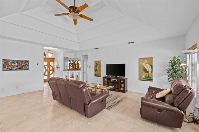 living room with light tile patterned floors, ceiling fan, and a raised ceiling