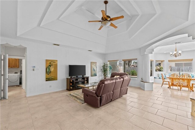 living room with ceiling fan with notable chandelier, light tile patterned floors, and a tray ceiling