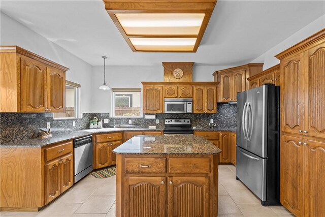 kitchen featuring stainless steel appliances, hanging light fixtures, a kitchen island, and backsplash