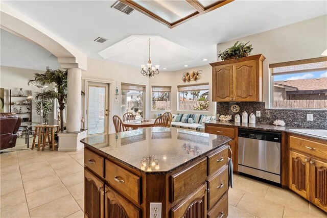 kitchen with stainless steel appliances, dark stone counters, a center island, and backsplash