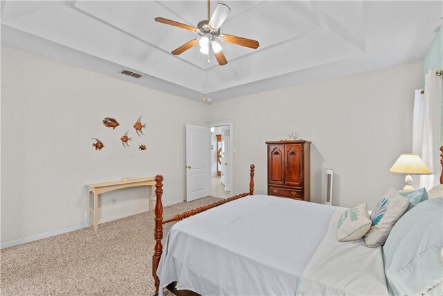 bedroom featuring light colored carpet, ceiling fan, and a raised ceiling