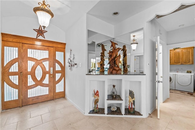 foyer entrance with visible vents, baseboards, light tile patterned flooring, and washing machine and clothes dryer