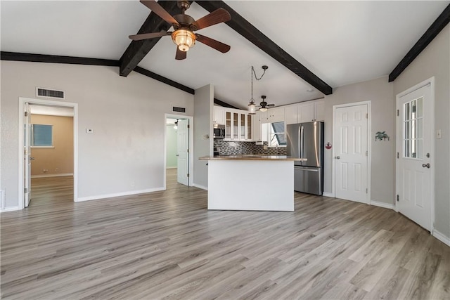 kitchen featuring hanging light fixtures, stainless steel appliances, tasteful backsplash, vaulted ceiling with beams, and white cabinets