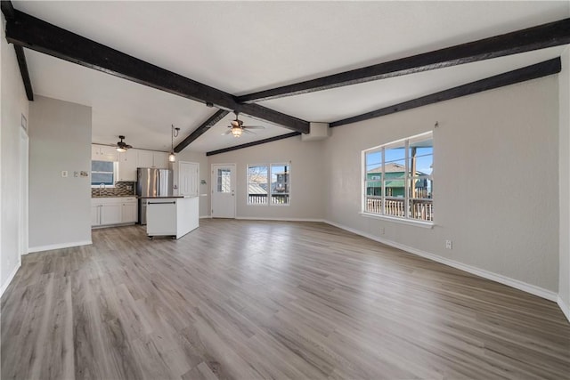 unfurnished living room with vaulted ceiling with beams, ceiling fan, and light wood-type flooring