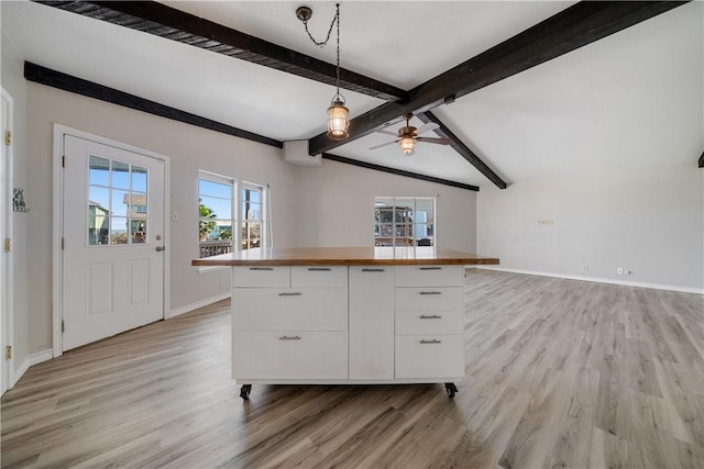 kitchen with butcher block counters, ceiling fan, lofted ceiling with beams, decorative light fixtures, and white cabinets