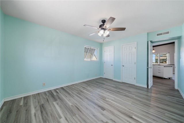 unfurnished bedroom featuring multiple windows, light hardwood / wood-style floors, and ceiling fan