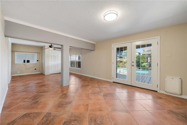 empty room with tile patterned floors, ceiling fan, french doors, and a textured ceiling