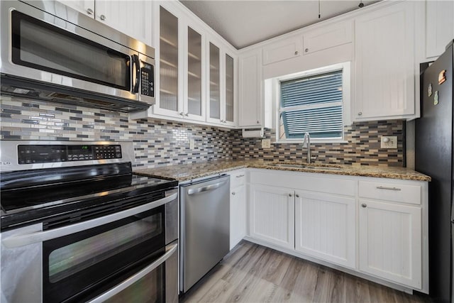 kitchen with light stone countertops, sink, stainless steel appliances, decorative backsplash, and white cabinets