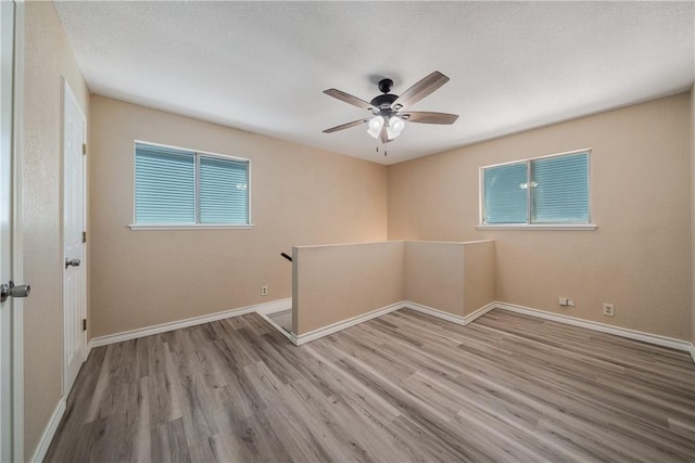 unfurnished room with light wood-type flooring, ceiling fan, and a healthy amount of sunlight