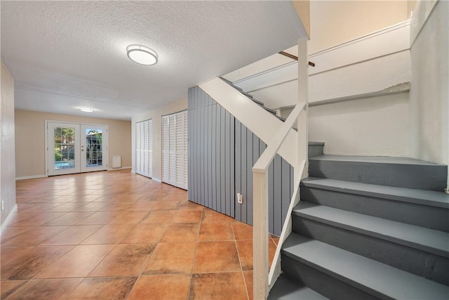 staircase featuring french doors and a textured ceiling