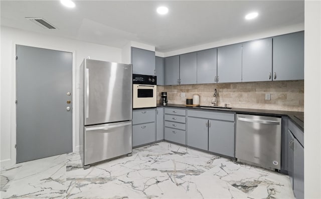 kitchen with gray cabinetry, decorative backsplash, sink, and appliances with stainless steel finishes