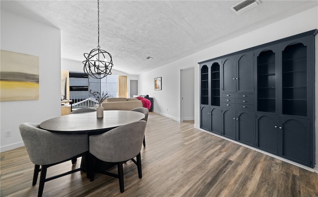 dining room featuring hardwood / wood-style flooring, a notable chandelier, and a textured ceiling