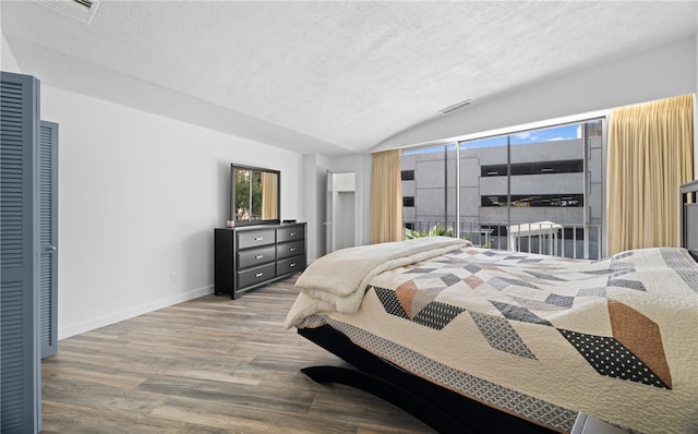 bedroom with a textured ceiling, a closet, wood-type flooring, and vaulted ceiling