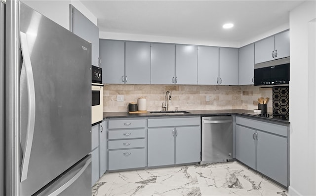 kitchen featuring gray cabinetry, backsplash, sink, and stainless steel appliances