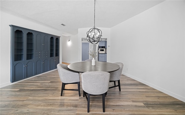 dining room with hardwood / wood-style floors and a notable chandelier