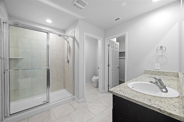 bathroom featuring tile patterned floors, vanity, toilet, and a shower with door