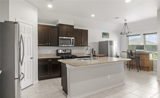 kitchen with stainless steel appliances, sink, an inviting chandelier, hanging light fixtures, and an island with sink